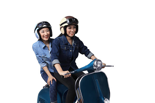 Two asian woman having fun when riding the scooter isolated over white background