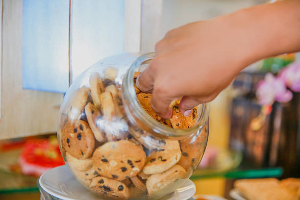 istock Young male human hands taking chocolate chip from inside jar 635825002