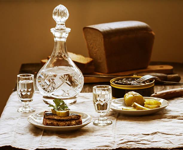 Sprat sandwiches of rye bread with vodka and salted cucumbers in a rustic wooden setting