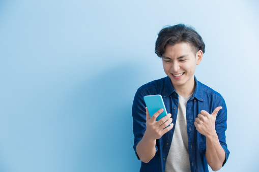 man student smile and use phone isolated on blue background,asian