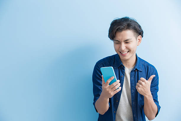 man student use phone man student smile and use phone isolated on blue background,asian male chinese student stock pictures, royalty-free photos & images