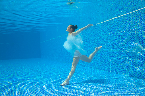 Ballet, ballerina dancing under the water. Underwater fashion, woman in white dress, relaxing in swimming pool. Summer fun, fantasy, modern dancing in water, Mermaid. Pool party.