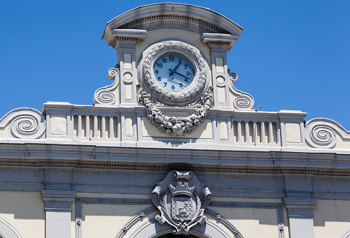 Detail on the facade of Carcassonne Train Station, the clock and a code of arms, France.