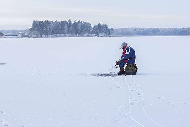 pêche sur glace. pêcheur assis sur un lac gelé pour pêcher - ice fishing photos et images de collection