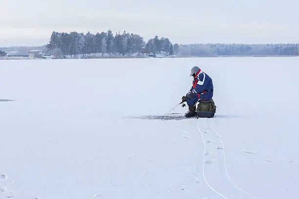 Ice fishing. Fisherman sitting on a frozen lake for fishing