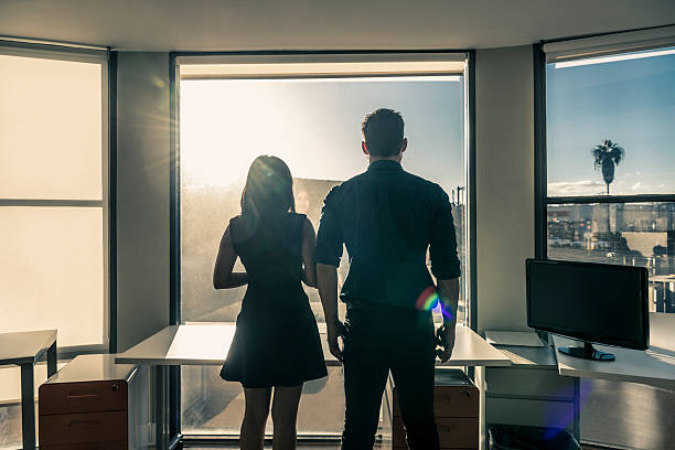 istock Two business people in modern office looking through window 635850488
