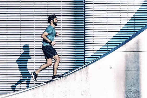 Photo of bearded sportsman running up on concrete wall in berlin
