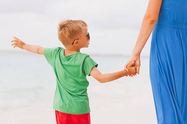 istock mother and son holding hands on beach 635863096