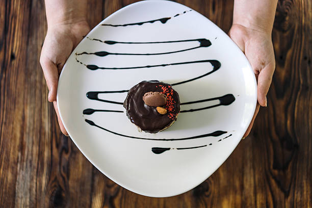 istock Women's hands holding a plate of dessert. 635863962
