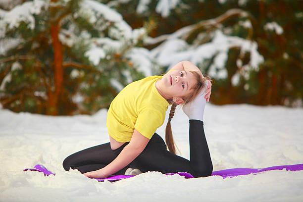 beautiful woman doing yoga outdoors in the snow stock photo