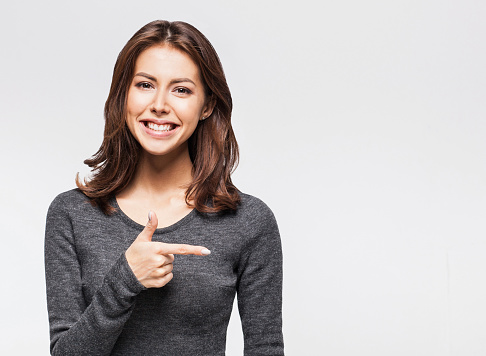 Young beautiful woman pointing at copy space