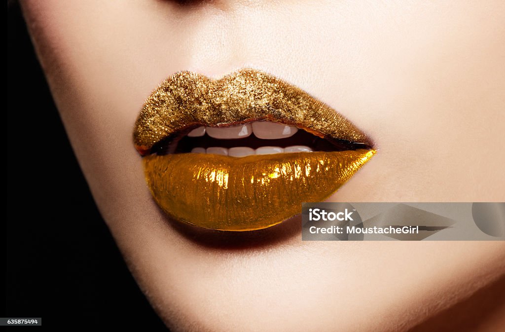 Closeup of gold artistic lips. Makeup cosmetic image. Closeup of gold artistic lips. Glitter upper lip and shiny lower lip. Makeup cosmetic image. Human Lips Stock Photo