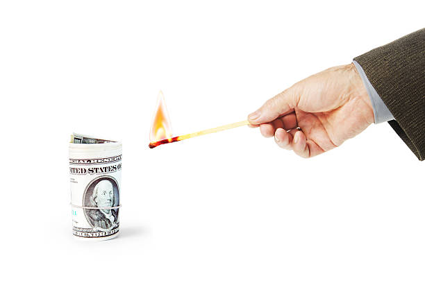 istock Man wants to set fire a roll of dollar banknotes 635877846