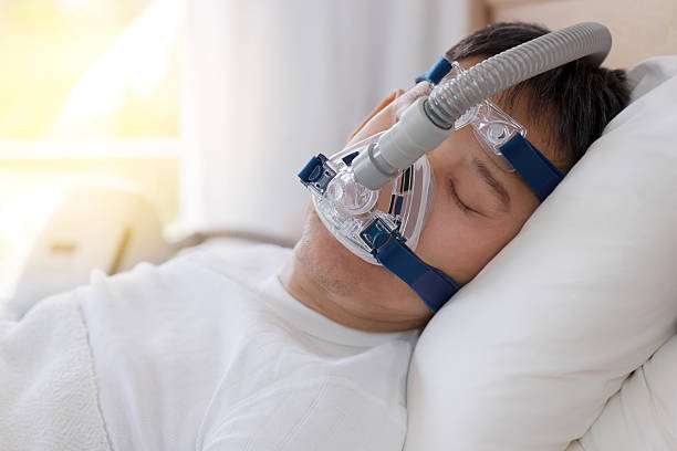 terapia de apnea del sueño, hombre durmiendo en la cama con máscara de cpap. - ventilador equipo respiratorio fotografías e imágenes de stock