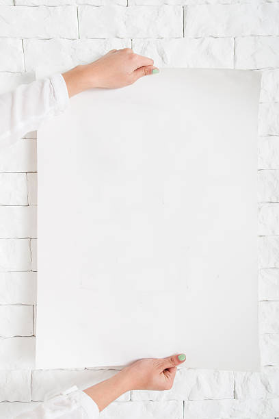 istock Blank poster in female hands against wall mockup 635878682