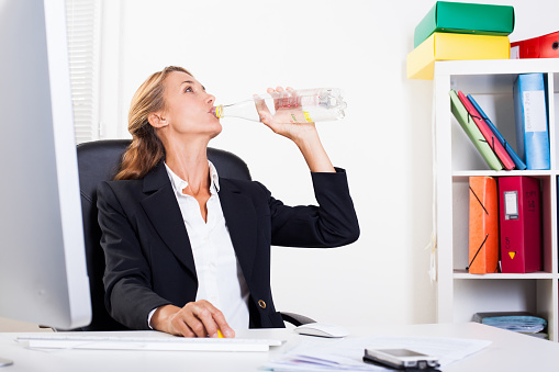 portrait of a woman drinking water sitting at the office