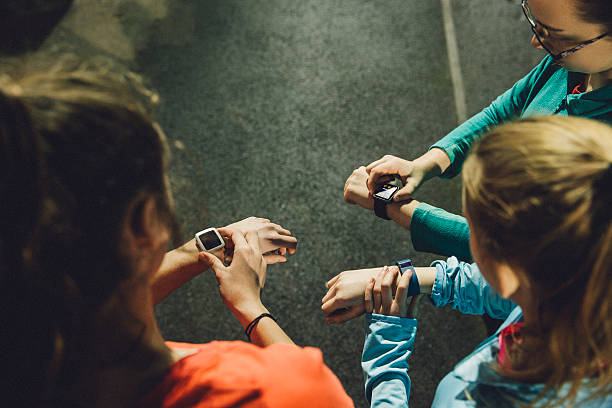 Using Smart Watches While Training Group of young athletes using smart watches during a training session on the running track. cardiac conduction system stock pictures, royalty-free photos & images