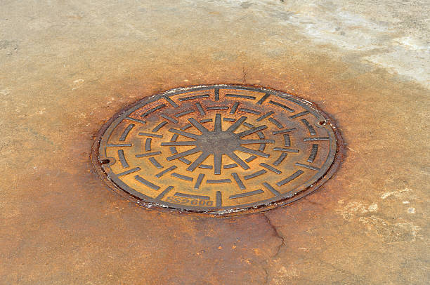 istock Rusty manhole cover on street, drain cover top view. 635894436