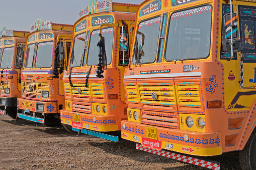 Gujarat, India - October 30, 2016: A fleet of trucks parked up on industrial land. India has the second largest network of roads in the world and its economy is heavily dependent upon road haulage. These trucks are decorated with a flamboyance typical of the region
