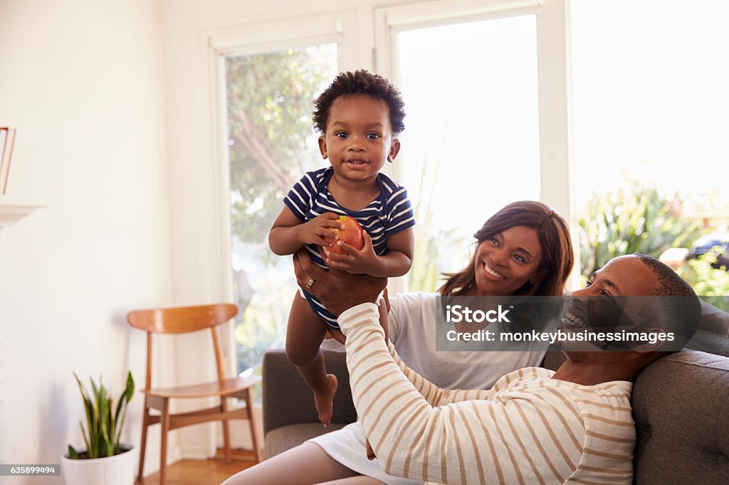 Padres e hijo jugando juego en el sofá en casa - Foto de stock de Familia libre de derechos