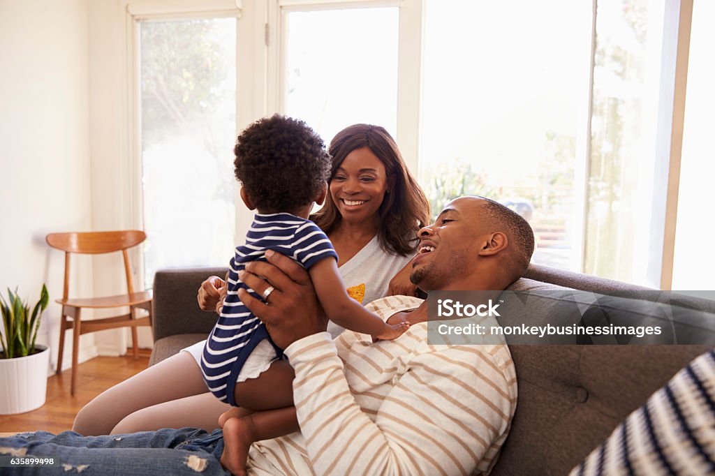 Parents And Son Playing Game On Sofa At Home Family Stock Photo