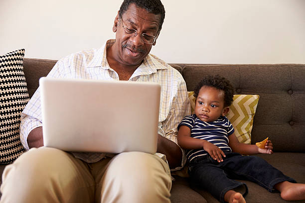 istock Grandfather And Grandson Sit On Sofa At Home Using Laptop 635899734