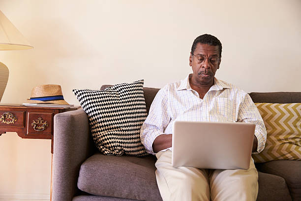istock Senior Man Sitting On Sofa At Home Using Laptop 635899772