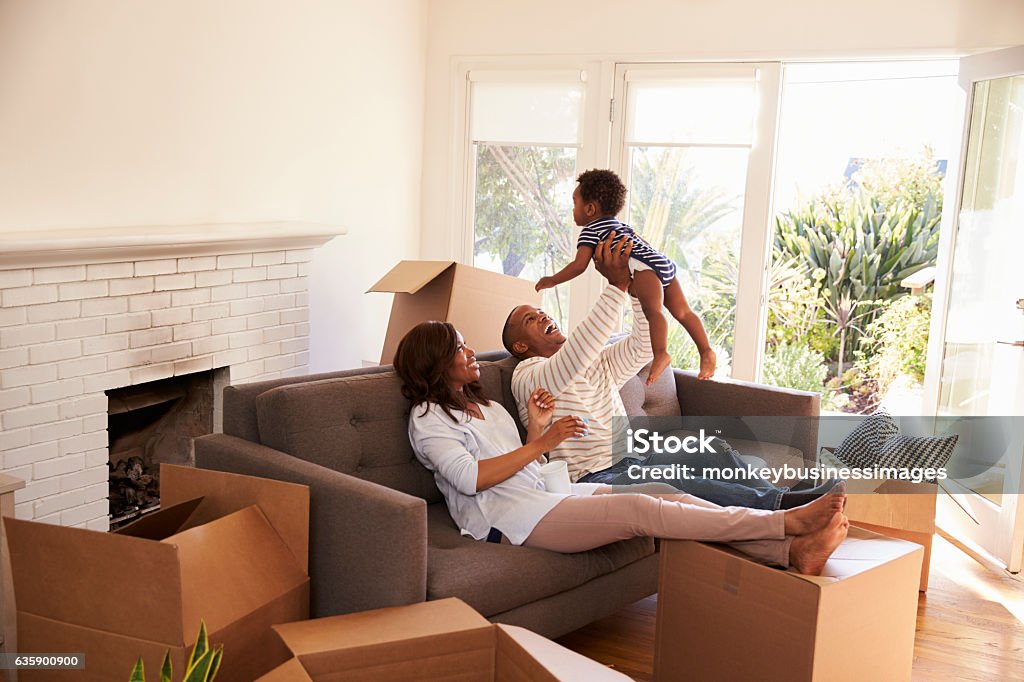 Parents Take A Break On Sofa With Son On Moving Day Home Ownership Stock Photo