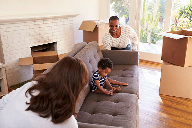 istock Parents Carry Son On Sofa Into New Home On Moving Day 635900926