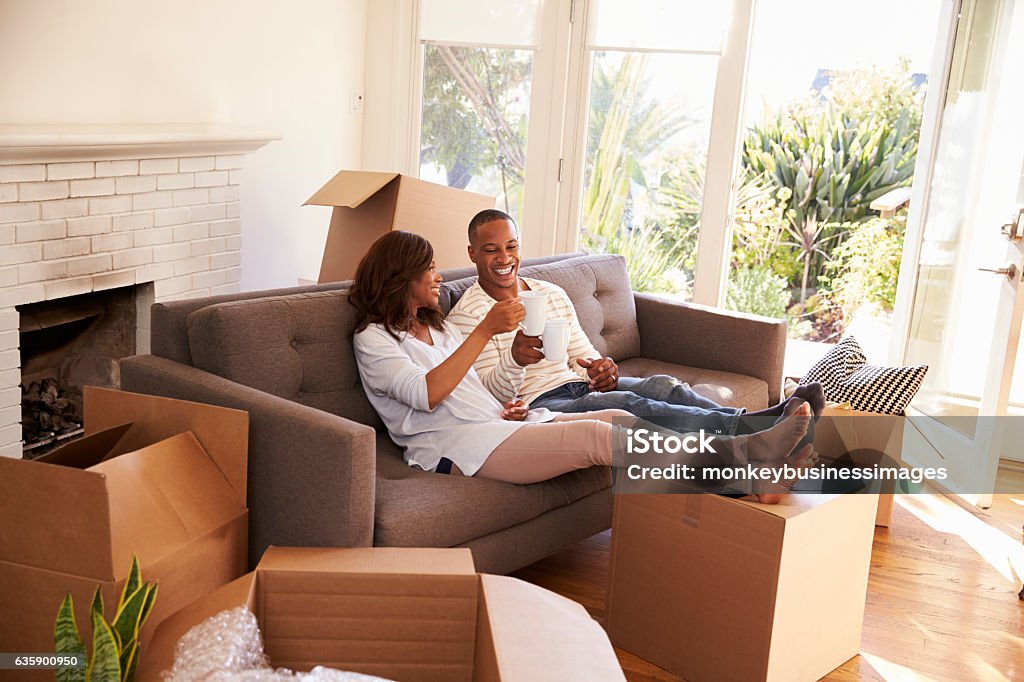 Couple On Sofa Taking A Break From Unpacking On Moving Day Moving House Stock Photo