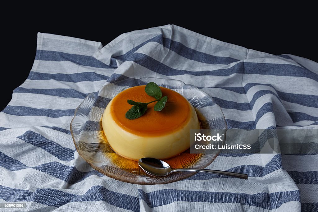 Vanilla flan served in glass dish on a kitchen cloth Vanilla flan served in glass dish on a kitchen cloth with black background Backgrounds Stock Photo