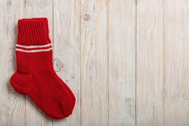 istock Knitted wool socks red color on light wooden background. 635902758