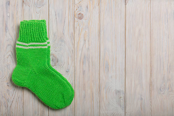 istock Knit green wool socks on light wooden background. 635903162