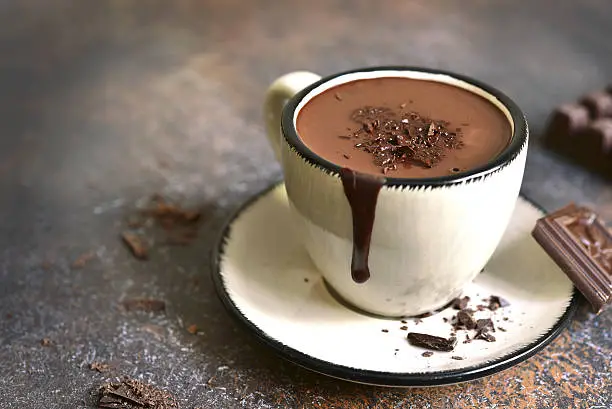 Thick spicy hot chocolate in a cup on a rustic background.