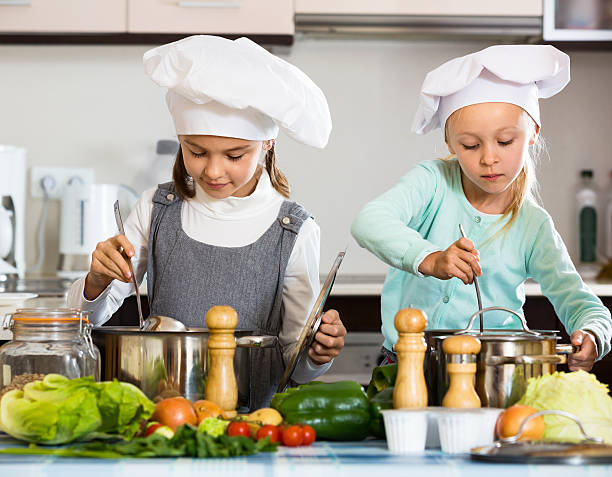 istock Two small happy girls cooking vegetable soup 635912140