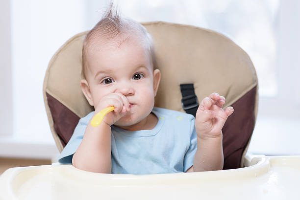 istock baby holding a spoon in his mouth 635912246