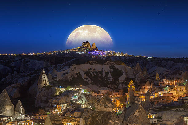 Full moon rising above Uchisar castle in ancient town, Cappadocia, Turkey. Elements of this image furnished by NASA nasa.gov