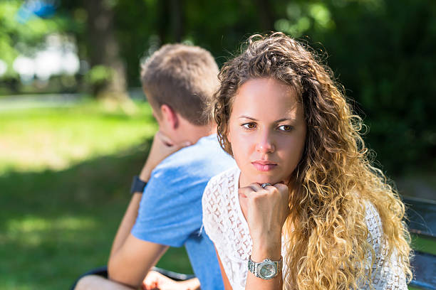 istock Sad young couple sitting on the bench at the park 635917096