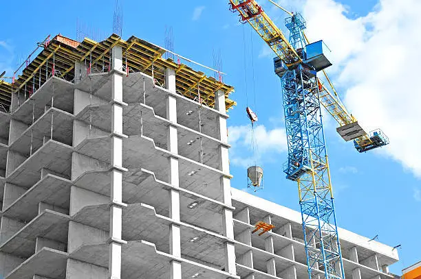 Crane and building under construction against blue sky