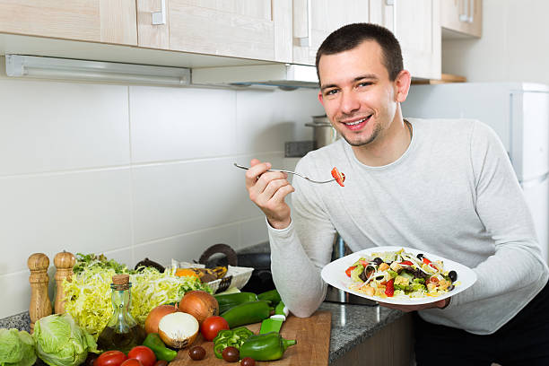 istock Man eating vegetable salad in kitchen 635925630