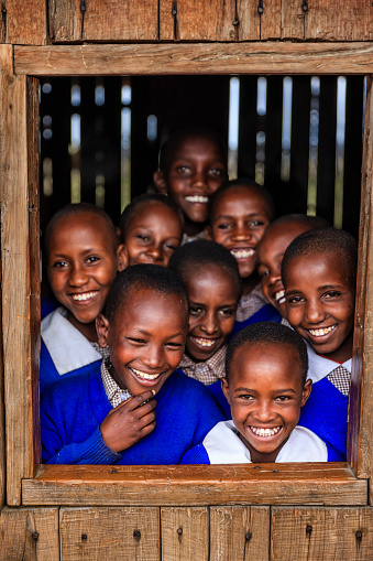 Group of African school children inside classroom in very remote school -they are standing inside classroom and looking through the window There is no light and electricity inside the classroom. School is located in very remote area in southern Kenya