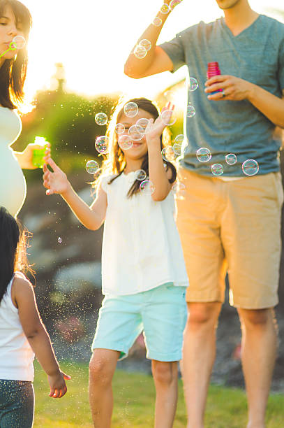 istock Ethnic family playing with bubbles outside on a warm 635933530