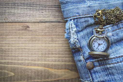 Pocket watch in Pocket Old Jean on Wooden Background with Copy Space