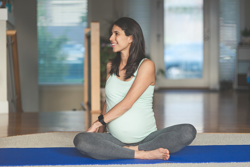Ethnic pregnant mother doing yoga in the home