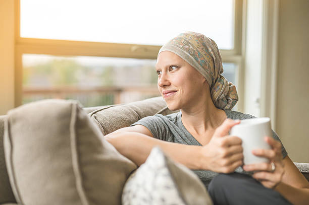 Ethnic young adult female cancer patient sipping tea Ethnic young adult female cancer patient sipping tea while at home chemotherapy drug stock pictures, royalty-free photos & images