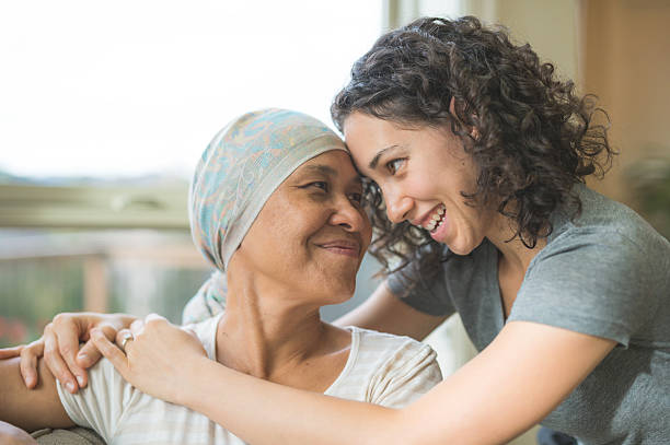 Ethnic adult female cancer patient hugging her daughter Ethnic adult female cancer patient hugging her daughter cancer cell stock pictures, royalty-free photos & images