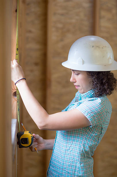 istock Latino female using a tape measure to check window 635938448