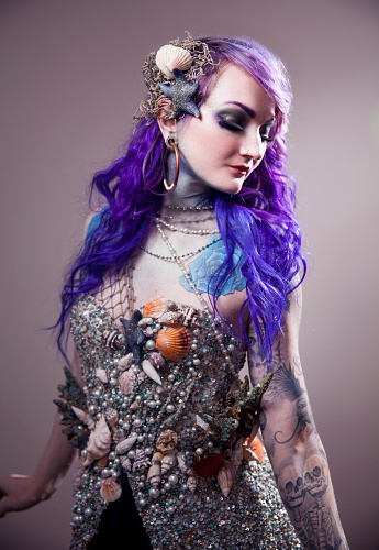 Beautiful woman with purple hair, wearing nature inspired, mermaid like, sea costume.