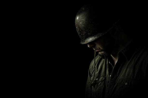 Praying Soldier Soldier in dramatically soft lighting with his head bowed in prayer. post traumatic stress disorder photos stock pictures, royalty-free photos & images
