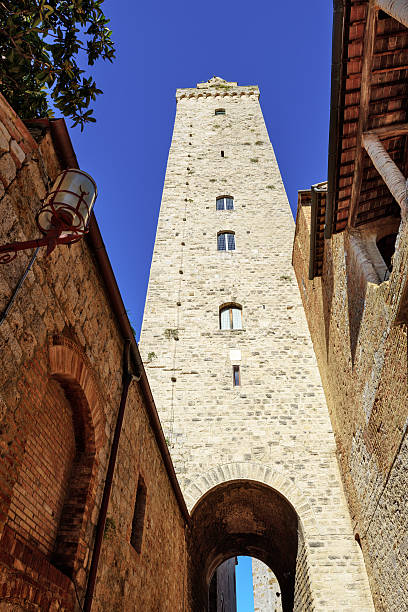 Historic stone towers and brick facades of San Gimignano, dramatic verticals under clear Tuscan sky.
